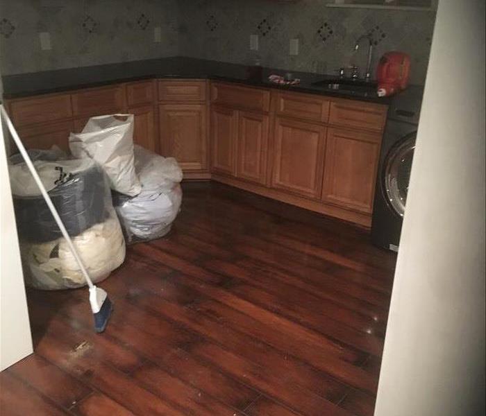 debris in bags, broom, wet still wood floor in a kitchen