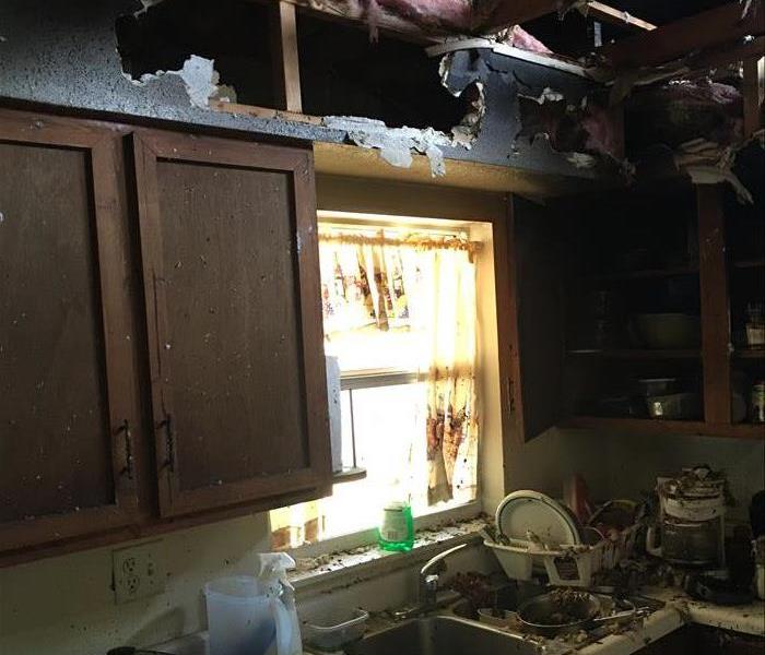 burned ceiling showing trusses, damage in the kitchen sink